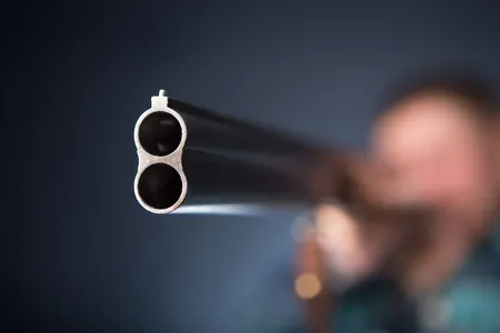 70646514-gángster-apuntando-con-una-escopeta-retrato-de-fondo-gris